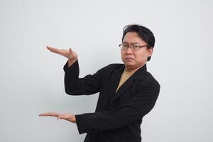 Unhappy and doubtful asian businessman doing smaller thing with 2 hands. Isolated white background photo