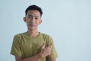 Asian young man showing pointing gesture with gesture and expression. Isolated on white background photo