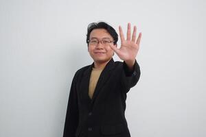 Smiling Asian Businessman with casual suit and shirt in studio showing stop, saying no or not accepting a deal hand sign, denial, refuse. isolated white background photo