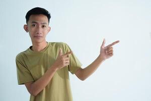 Asian young man showing pointing gesture with gesture and expression. Isolated on white background photo