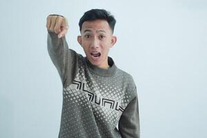 Asian young man showing pointing gesture with gesture and expression. Isolated on white background photo