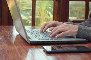 Close up side view young man typing with laptop on table in livingroom, remote working. Digital nomand photo