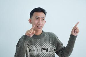 Asian young man showing pointing gesture with gesture and expression. Isolated on white background photo