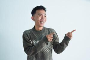 Asian young man showing pointing gesture with gesture and expression. Isolated on white background photo