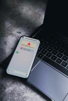 Smartphone laying on laptop receives message from suspected number scam. Unwanted anonymous call. Fraud and phishing phone concept. Message from stranger. photo