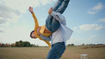Happy Caucasian family playful laughing male man father parent dad spinning carrying arms holding spin whirling little boy son child kid swing play plane flying game having fun rural nature field farm video