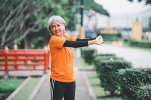 white-haired elderly person exercising in the park early in the morning. photo