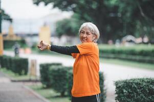 white-haired elderly person exercising in the park early in the morning. photo