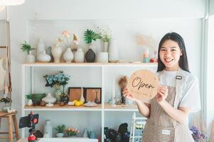 Smiling online small business owner holding a sign saying Open and happily working at a courier business offering orders and products to customers.Online retailer - online shopping. photo