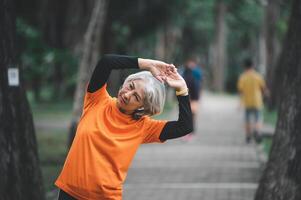 white-haired elderly person exercising in the park early in the morning. photo