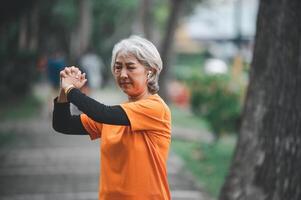 white-haired elderly person exercising in the park early in the morning. photo
