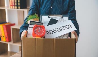 Female firm employee leaving the office with cardboard boxes containing office supplies and personal items after quitting to find a new job, being fired, or being fired from the company. photo