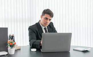 businessman sitting at worktable at modern office analyzing company performance, finance and investment photo