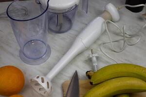 Blender on table with containers for grinding and fruits for making smoothies. Ingredients for healthy drink with vitamins for strengthening human health photo