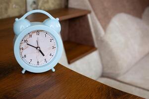 Alarm clock to notify bedtime is on shelf of home sofa in rest room, health benefits of sleep and right time to wake up photo