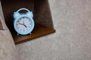 Home alarm clock stands on shelf next to the sleeping area on the sofa in domestic room, control person sleep with an alarm clock photo