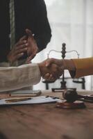 Lawyer shaking hands with a client making about documents, contracts, agreements, cooperation agreements with a female client at the lawyer's desk and a hammer at the table. photo