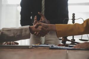 Lawyer shaking hands with a client making about documents, contracts, agreements, cooperation agreements with a female client at the lawyer's desk and a hammer at the table. photo