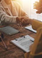 Lawyer shaking hands with a client making about documents, contracts, agreements, cooperation agreements with a female client at the lawyer's desk and a hammer at the table. photo