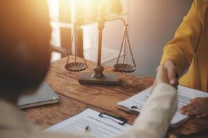 Lawyer shaking hands with a client making about documents, contracts, agreements, cooperation agreements with a female client at the lawyer's desk and a hammer at the table. photo