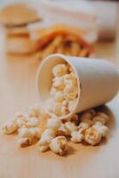 A bucket of popcorn, top-view, warm colors, light brown wooden background, flat lay, daylight macro close-up photo