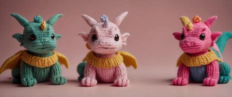 three small knitted dragons on a pink background. photo