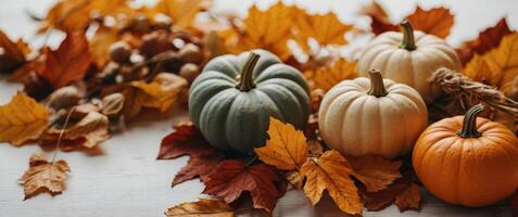 Pumpkins and fall leaves on white table background Thanksgiving day and Halloween concept Fall harvest and crop Flat lay autumn composition with copy space. photo