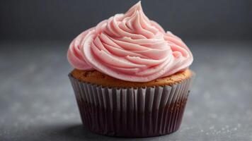 Delicious Pink Frosted Cupcake With Swirls of Creamy Icing on a Gray Background. photo