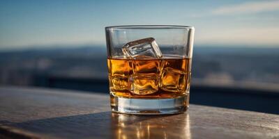 A glass of whiskey is sitting on a table with a blue sky in the background. photo