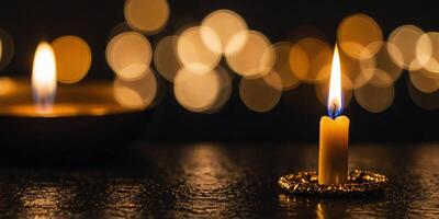 A gold candle with a flame is lit on a dark surface. photo