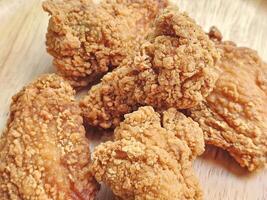 Close up, group of fried chicken wings arranged on wooden plate photo