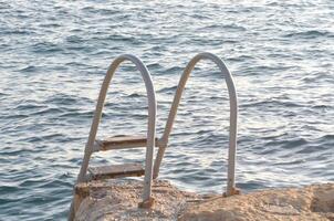 A pair of metal steps leading to the ocean photo