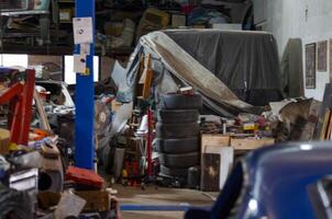 A mechanic shop garage filled with tools, equipment, and vehicles in various stages of repair. The workspace is a hub of automotive activity, featuring an array of tires, toolboxes, and mechanical photo