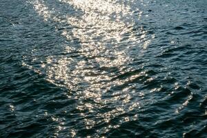 Sunset Reflections, Rippling Water Surface with Golden and Blue Hues at Evening sea wave abstract texture sunlight blue and golden pattern blurred background. photo