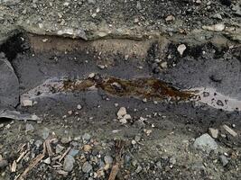 contaminated water with coal on coal yard area. A small stream of water flows through a gravel path, creating a natural drainage channel. photo