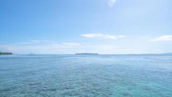 Tranquil Ocean Landscape. A panoramic view of a tranquil ocean with a clear blue sky and a small island in the distance. photo