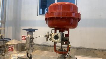 Industrial Control Valve pneumatic System. Close-up of an industrial valve system with red and silver components. The valve is designed to control the flow of liquids or gases within a process. photo