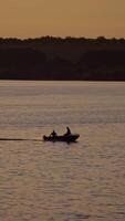Motor boat floating in water on the forest background at dusk. Two people in a boat swimming along the river in the evening. Vertical video