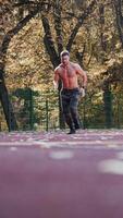 en bonne santé athlète est fonctionnement dans le stade. Jeune sportif est impliqué dans sport fonctionnement sur le l'automne des arbres Contexte. vue de dessous. verticale video