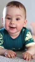 Happy beautiful boy clapping hands over the floor. Smiling child being active. Close up. Blurred backdrop. Vertical video
