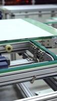 Close-up work of automated equipment for producing solar panels. Modernized factory with innovative technologies indoors. Vertical video