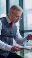 Thoughtful businessman working on computer in front of the window with city view. of working process in big company. Vertical video