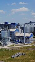Modern factory with elevators. Industrial area for agribusiness on field in summer. Metal containers for storing grains. Aerial view. Vertical video