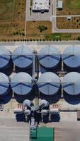 Grain silos. Aluminum containers for storage harvest. Railway with freight trains on industrial territory. Silver grain terminals on field. Top view. Agribusiness concept. Vertical video