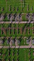 High voltage lines on green field. Flight over power transmission lines. Huge territory with steel pillars for electricity. Top aerial view. Vertical video