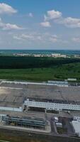 Panoramic view of industrial zone on fields. Large territory of modern factory on green nature background in the countryside. Aerial view. Vertical video