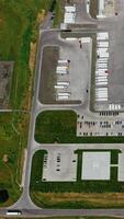 Industrial zone on field. View from above on roofs of a modern manufacture with many car parking places. Aerial view. Slow motion. Vertical video