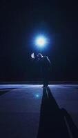 Elegant man on stage. Dark silhouette of a stylish man wearing hat performing on the scene in theatre at spotlight. View from the stage. Vertical video