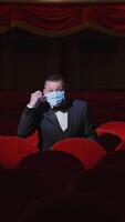 Man in empty theater. Rich man in suit taking off facial mask and says something among rows of red seats in the theater without audience. World crisis at pandemic. Vertical video