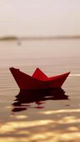 Red paper boat floating alone with the slow motion in the river at sunset. Lovely kid's origami ship on water surface in the evening. Close-up Vertical video